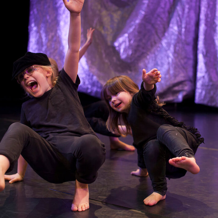 Två barn dansar nära golvet med bara en hand och en fot i golvet.
